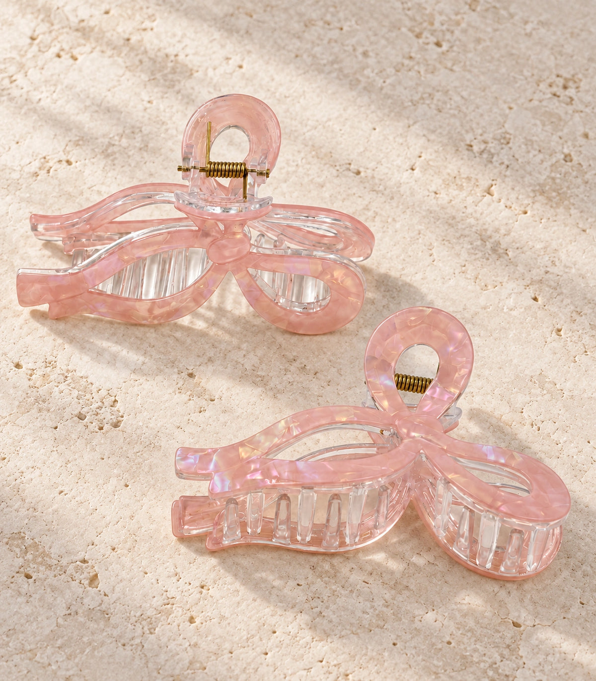 JIMIKI Iridescent Openwork Bow Hair Claw Clips in Pink, editorial flat lay #color_pink