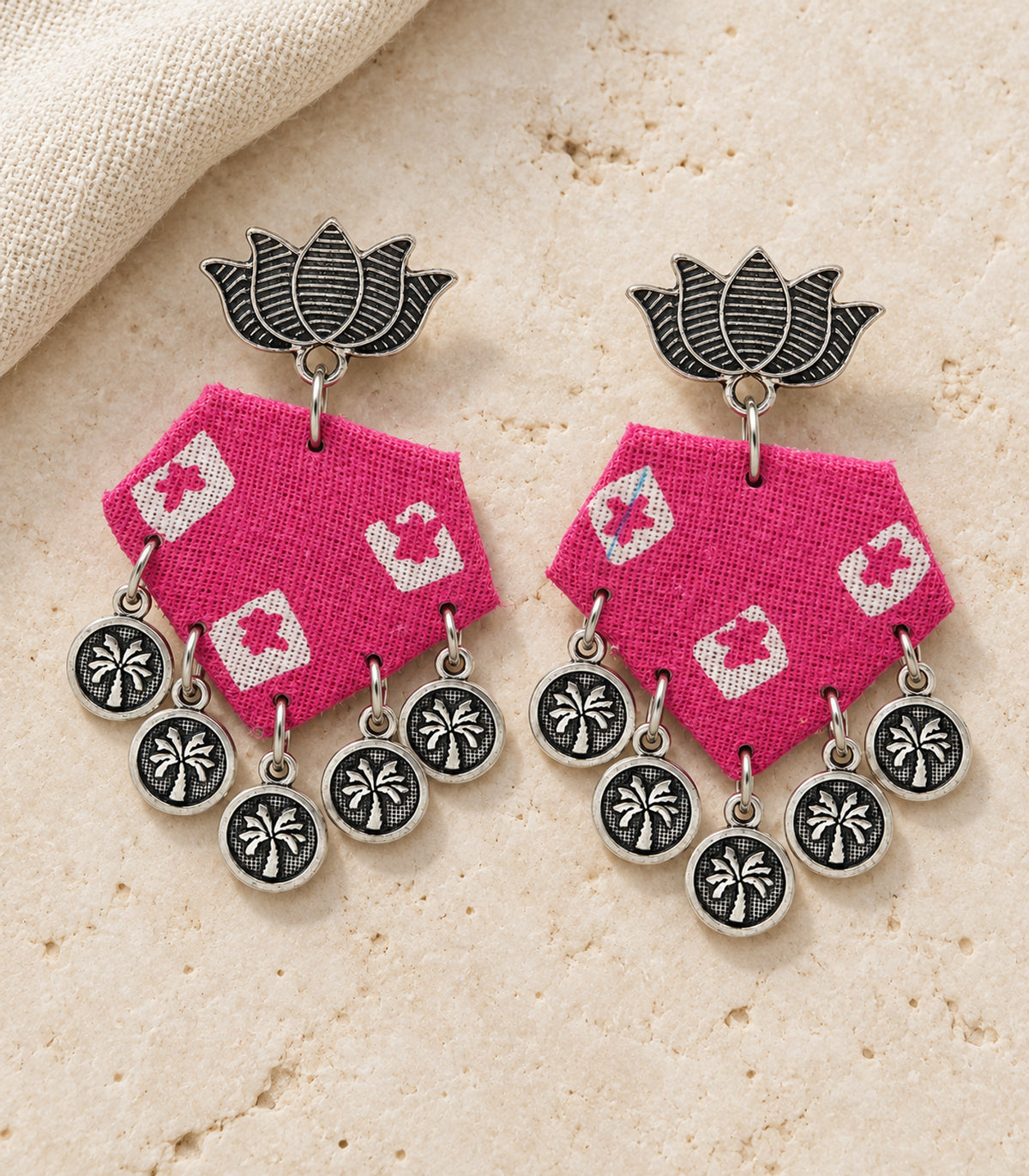Pink and ivory lotus hexagon coin earrings — editorial flatlay view