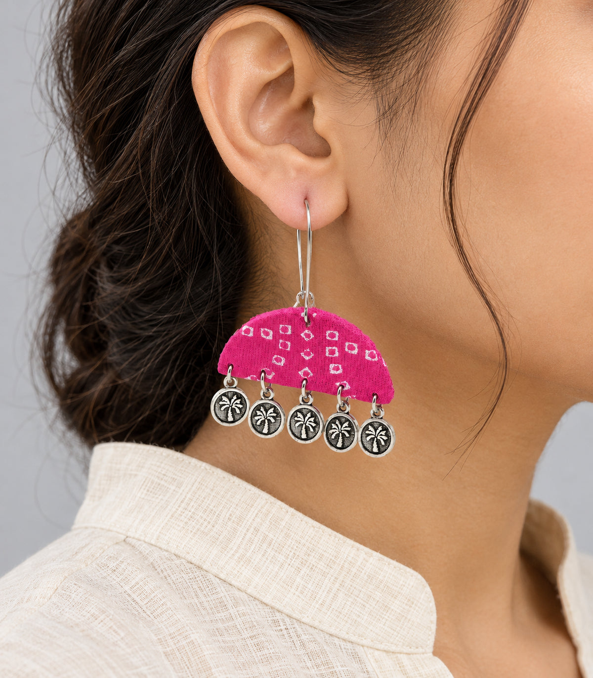 Close detail of pink printed semicircle earring and five hanging tree coins