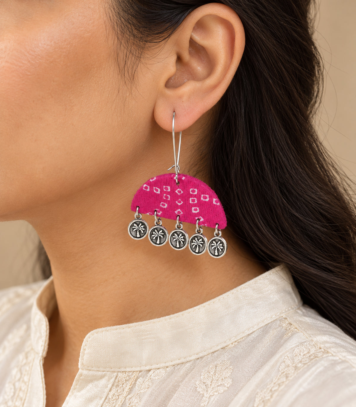 Pink fabric five-coin earring worn on one ear, side view