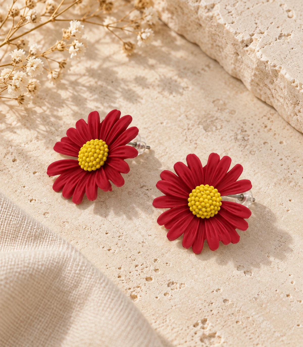 JIMIKI Red yellow centre daisy stud earrings, matching pair on a styled stone surface #color_red