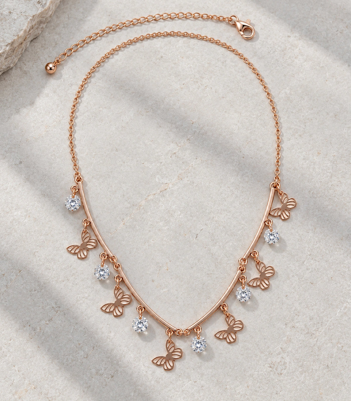 JIMIKI Rose Gold Butterfly Crystal Charm Collar Necklace in Rose Gold - editorial flatlay #color_rose-gold