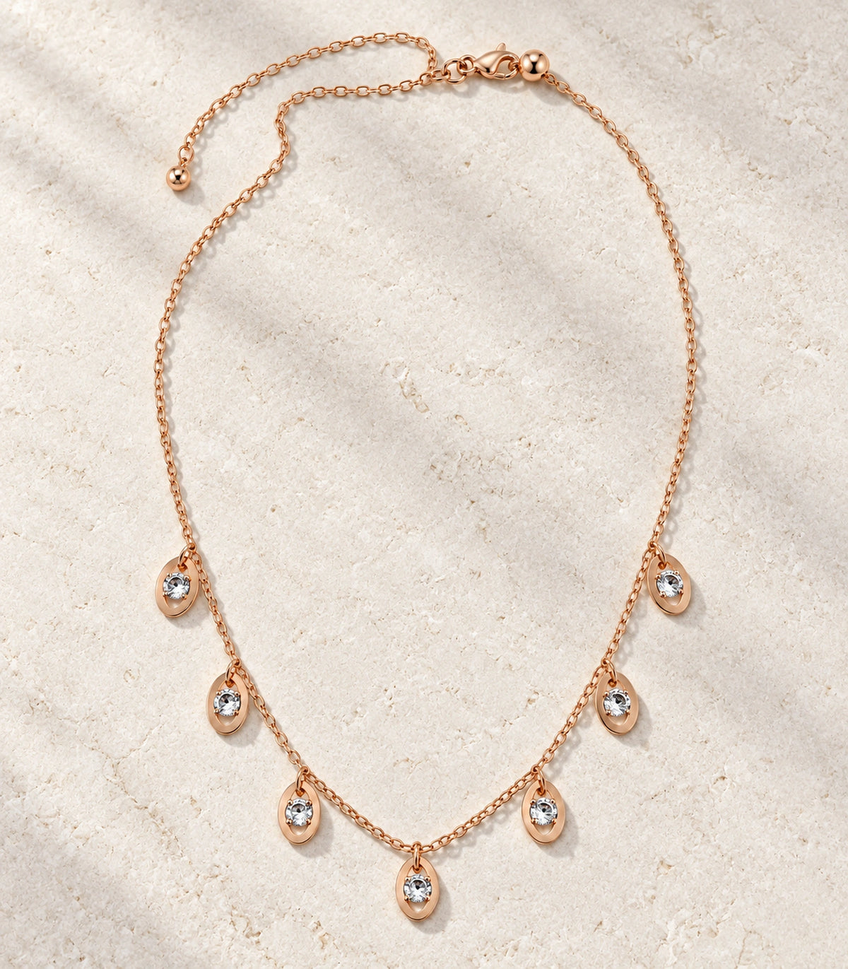 JIMIKI Rose Gold Oval Crystal Charm Necklace in Rose Gold - editorial flatlay #color_rose-gold