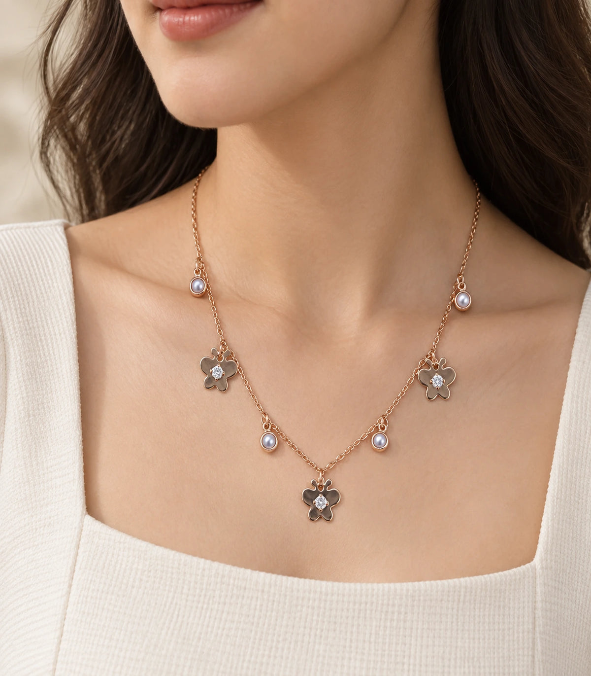 JIMIKI Rose Gold Pearl Effect Butterfly Charm Necklace - butterfly charm necklace in an editorial worn view #color_rose-gold