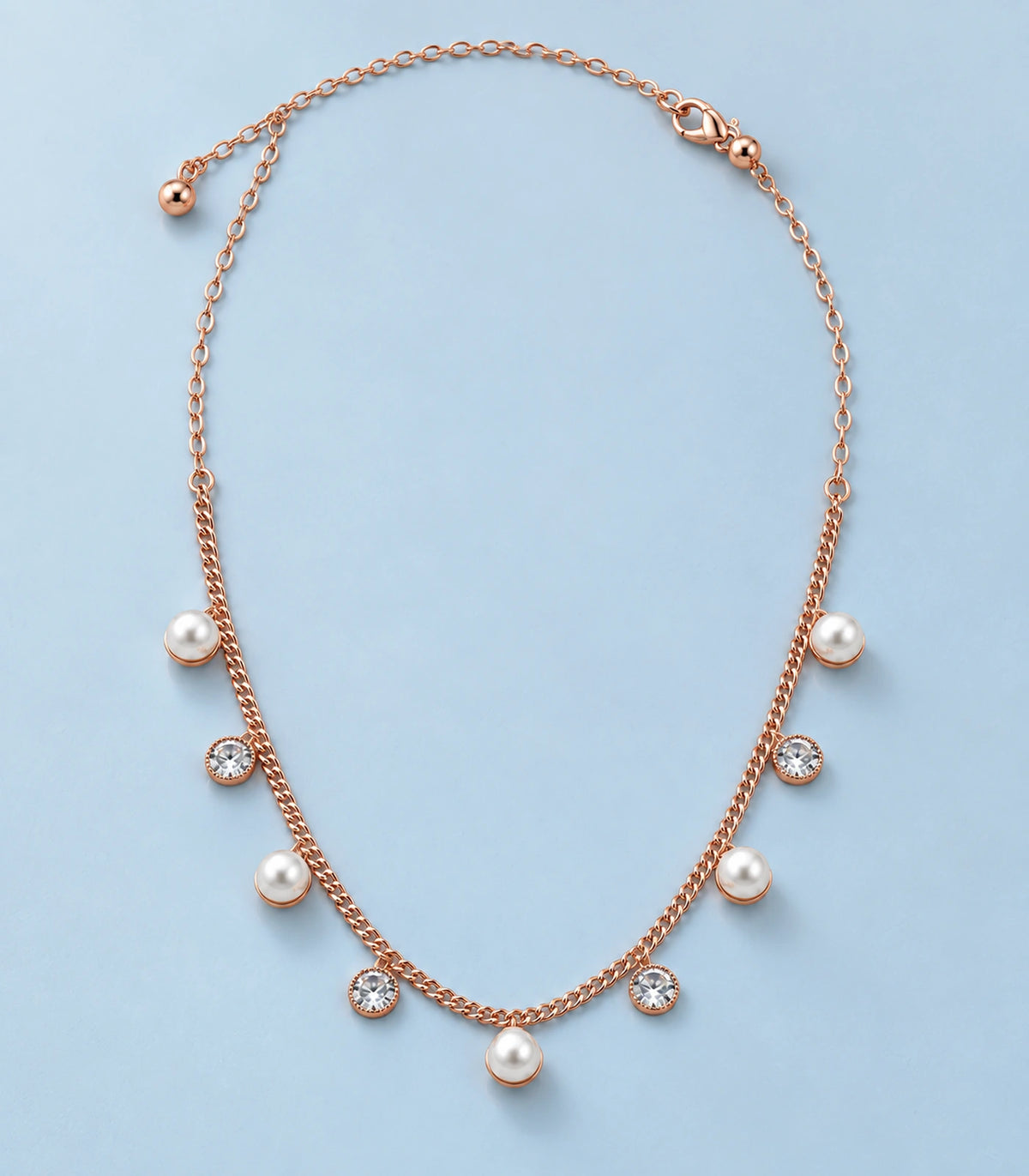 JIMIKI Rose Gold Pearl Round Crystal Charm Necklace in Rose Gold - editorial flatlay #color_rose-gold