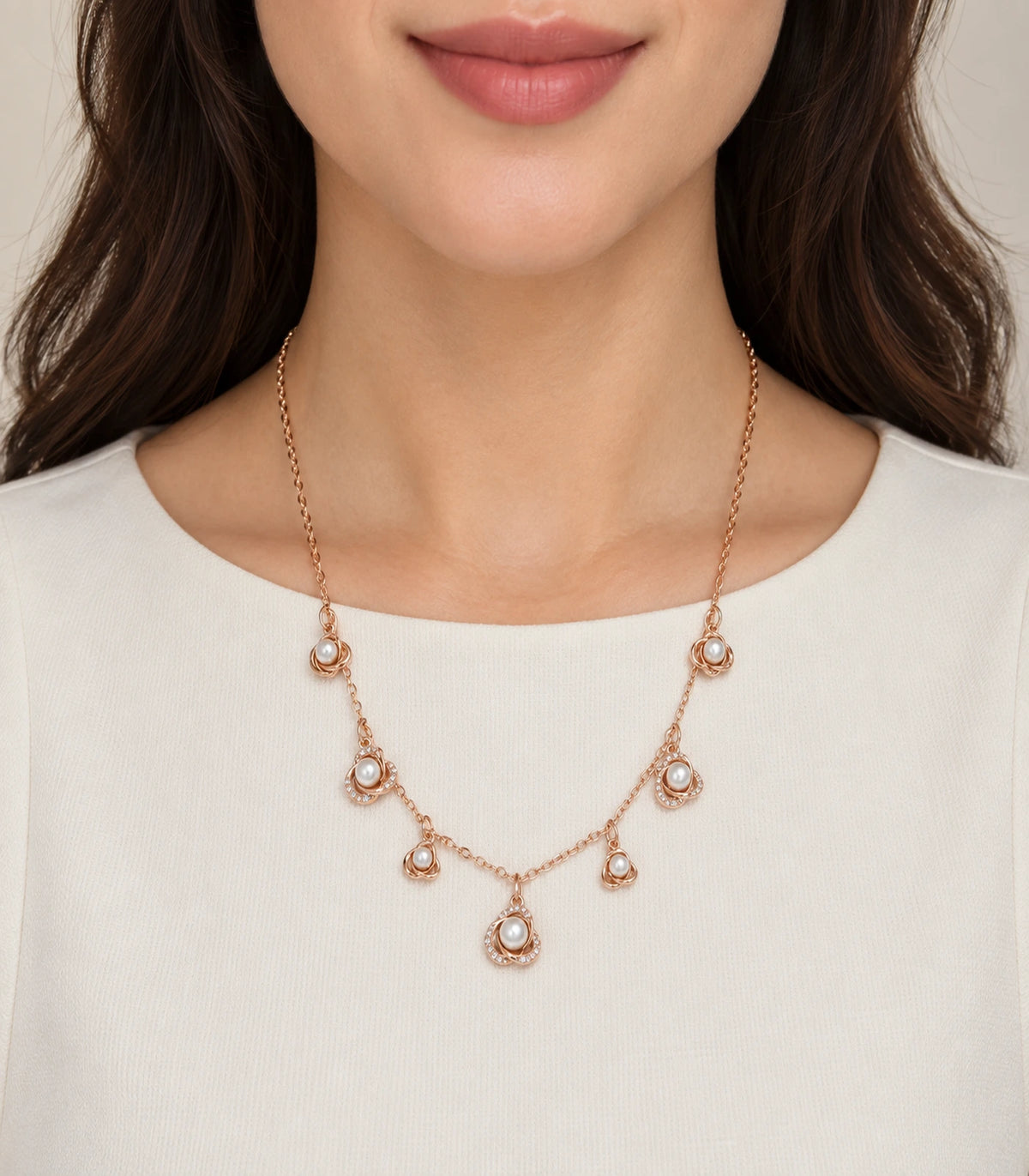 JIMIKI Rose Gold pearly rose charm necklace, worn over a plain cream top #color_rose gold