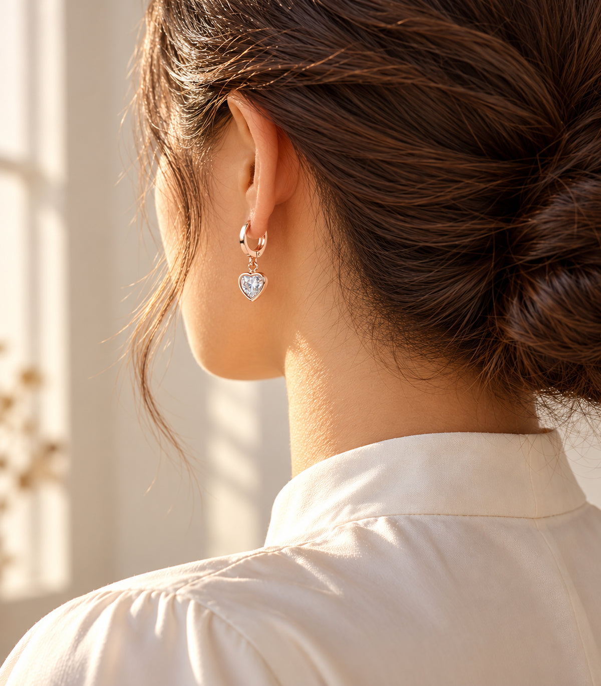One clear heart charm hoop from the three-pair set worn with a cream high-neck blouse #Color_Rose Gold Tone