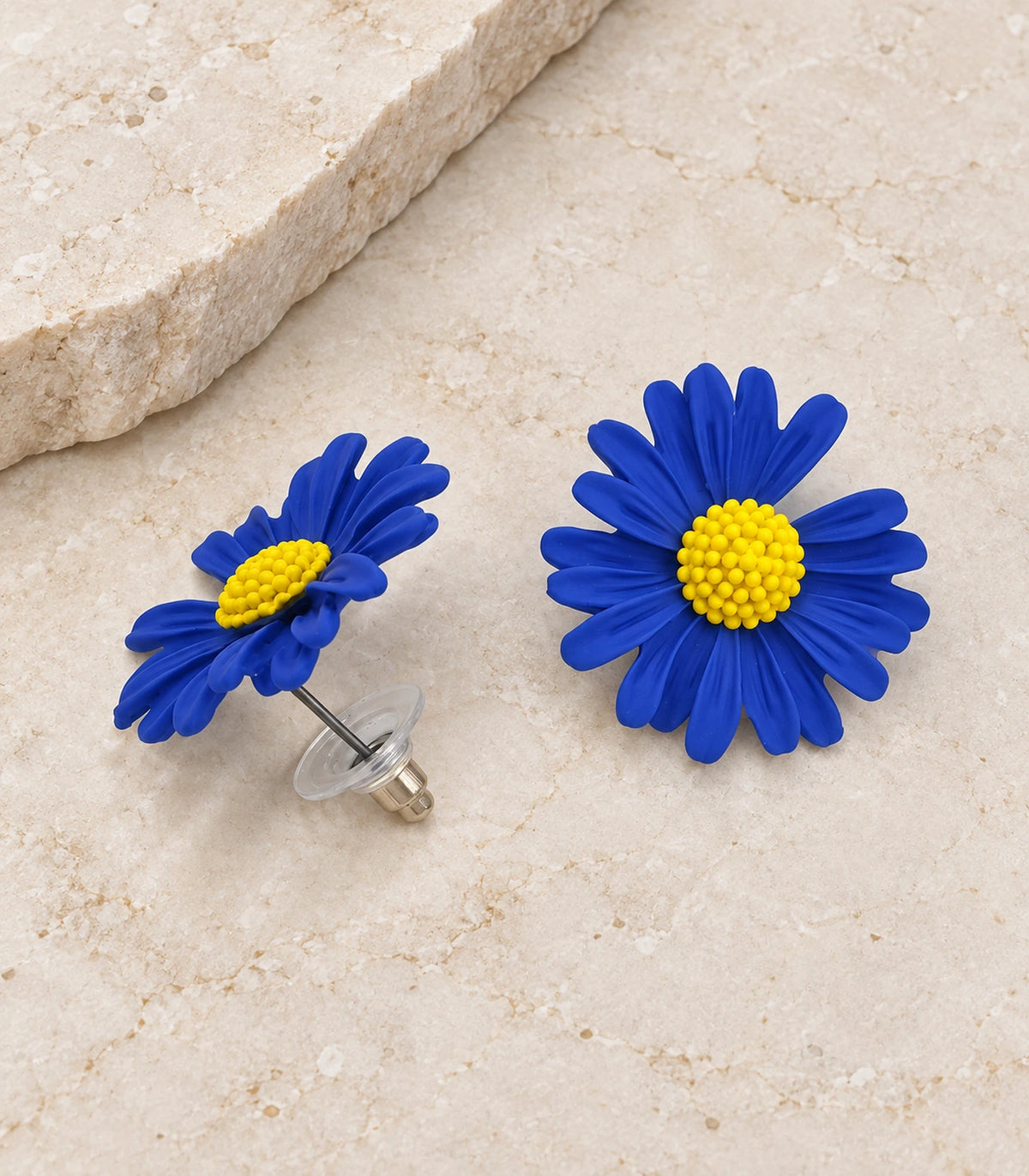 JIMIKI Royal Blue yellow centre daisy stud earrings, matching pair on a styled stone surface #color_royal blue