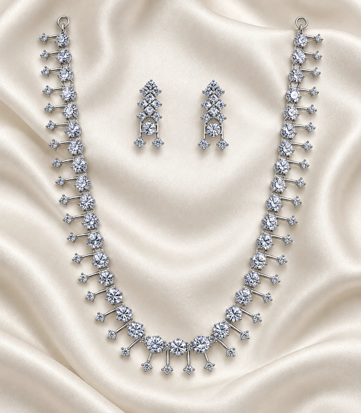 Silver-tone clear fringe necklace and matching earrings arranged on cream fabric