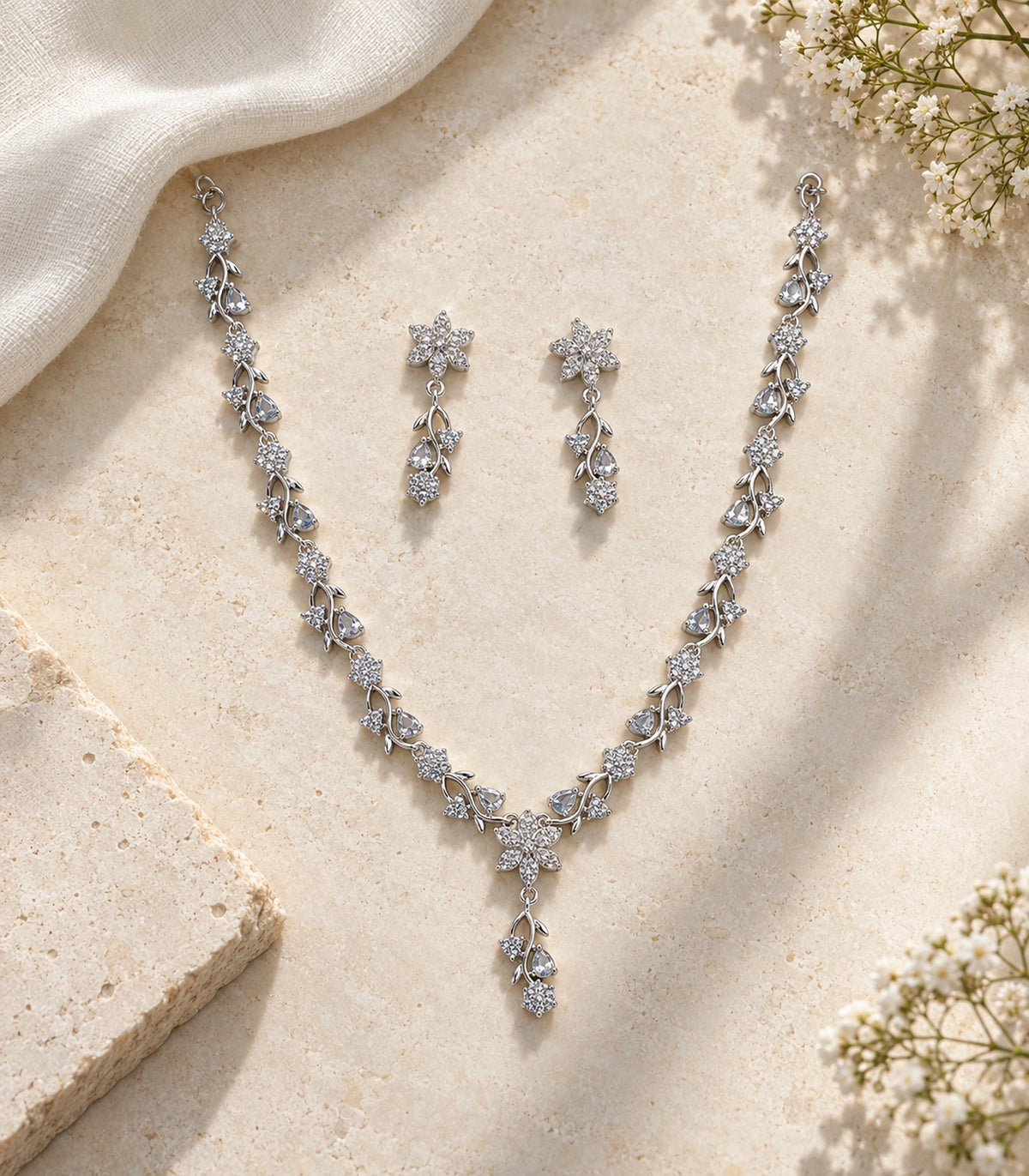 Complete silver-tone clear floral necklace and matching earring pair on a stone flatlay