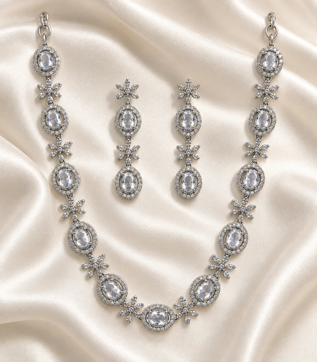 Silver clear oval floral necklace set arranged on ivory fabric