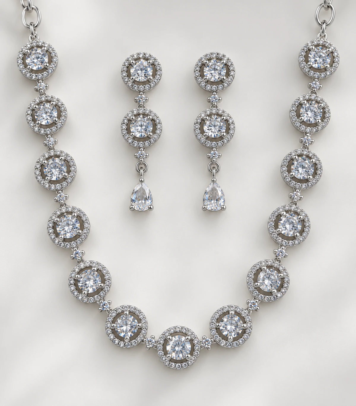 Close detail of clear round halo motifs, small connectors and matching pear-drop earrings
