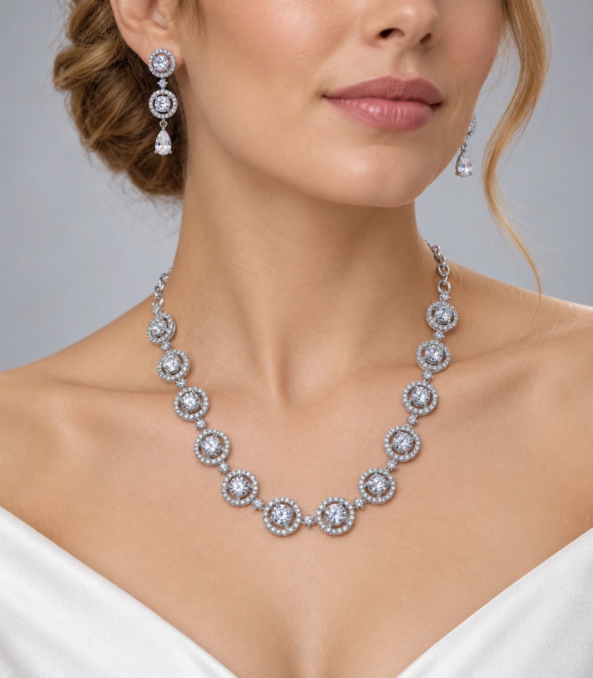 Silver-tone clear round halo necklace set styled with matching pear-drop earrings