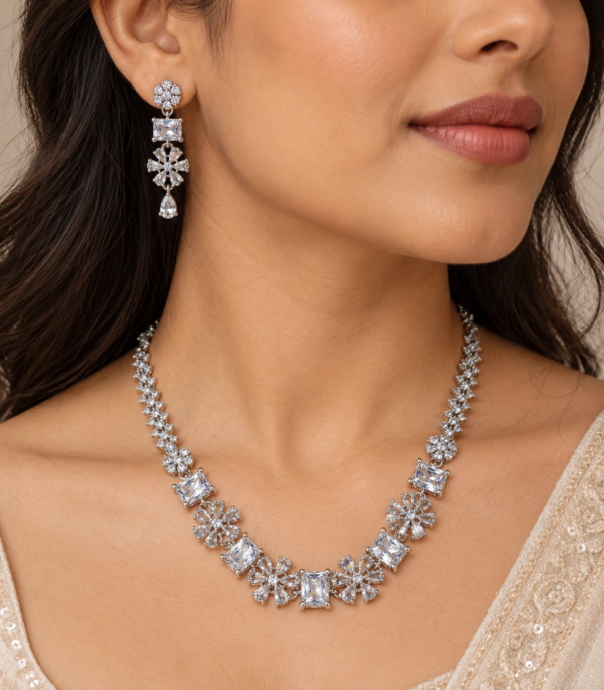 Close worn view of the floral and rectangular clear crystal necklace and complete matching teardrop earring