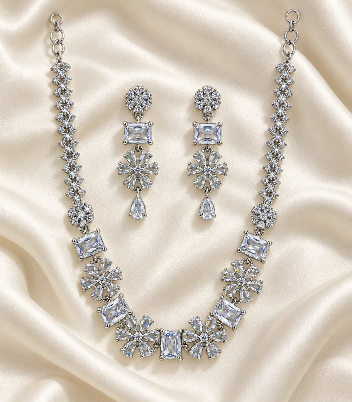 Complete silver-tone clear crystal necklace and matching earring pair arranged on ivory fabric