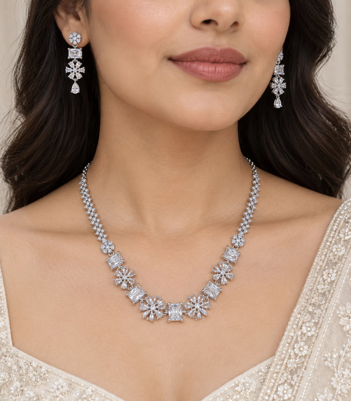 Silver-tone clear crystal necklace set worn with matching earrings and an ivory saree