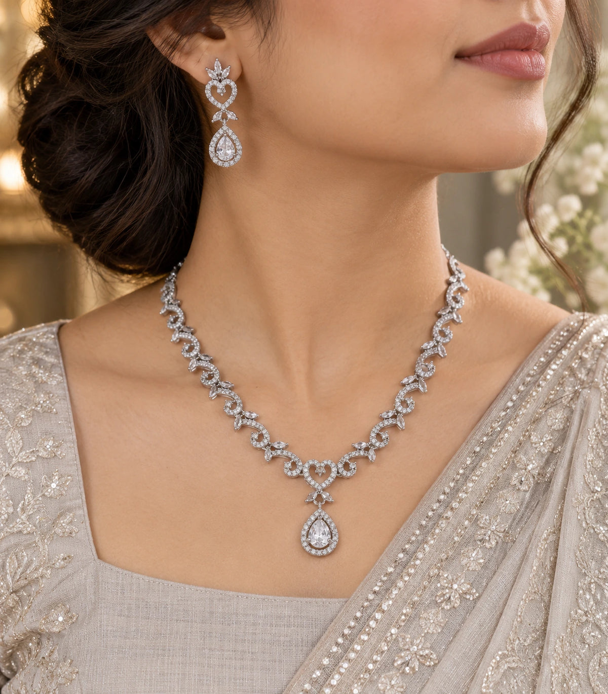 Three-quarter worn view of the silver-tone clear scrolling necklace and matching heart teardrop earring