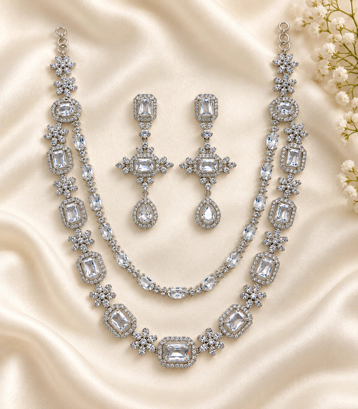 Silver-tone double-layer necklace and matching earring pair on cream fabric