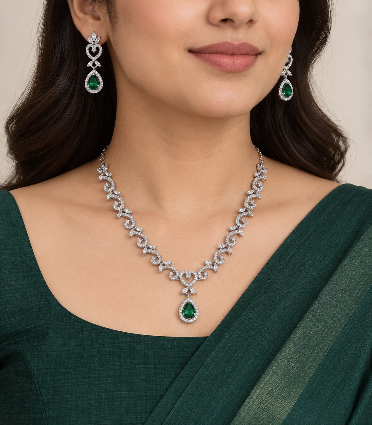 Silver-tone necklace and green teardrop earrings worn with a dark green outfit