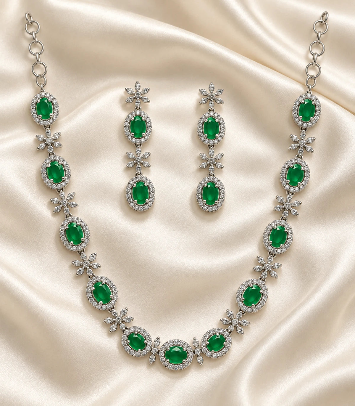 Silver-tone green oval necklace and matching earring pair arranged on ivory fabric