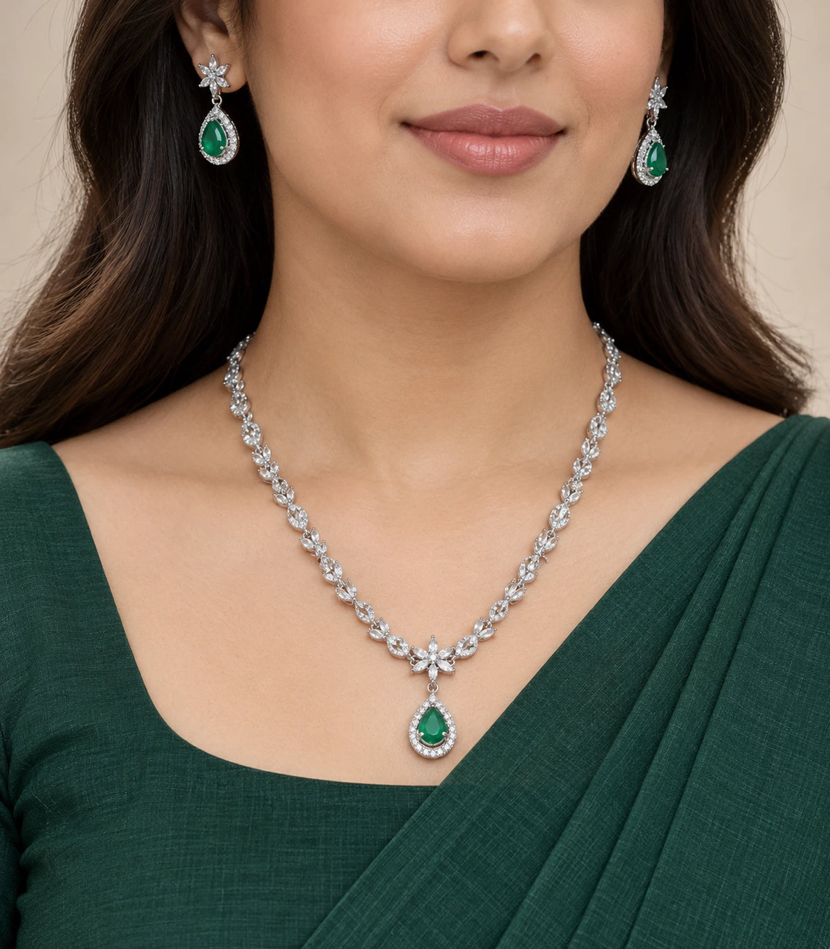 Silver-tone floral necklace set with emerald-green teardrop accents worn with a green outfit