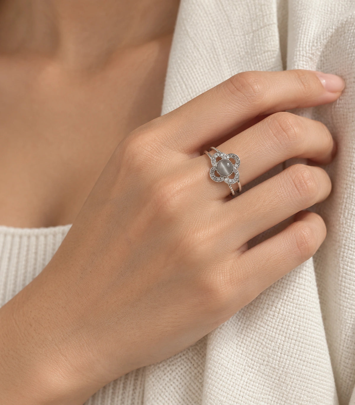 Silver grey clover halo ring worn in a wider cardigan composition