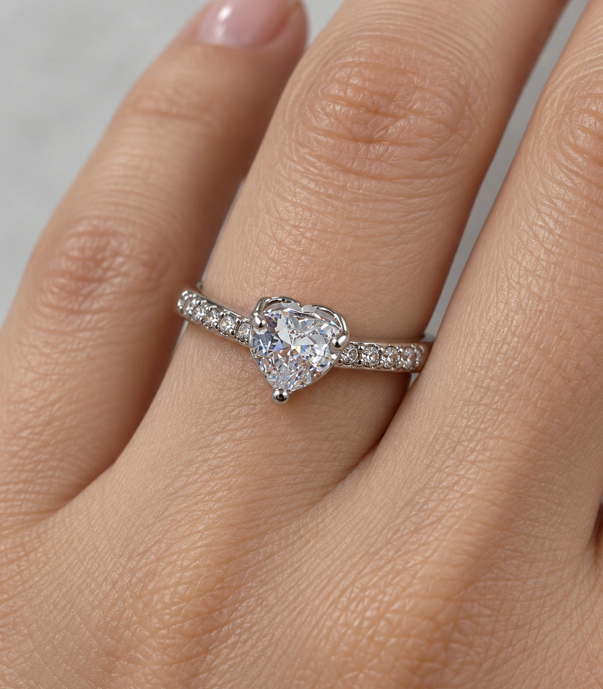 Worn closeup of the clear heart centre and pavé shoulders of the silver-tone ring