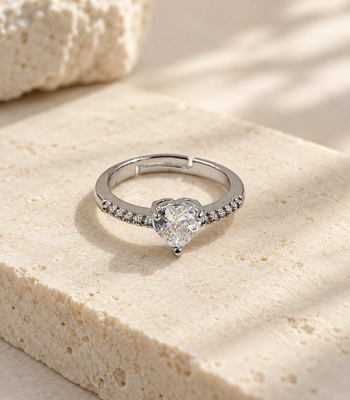 Complete silver-tone heart crystal pavé ring styled on a stone surface