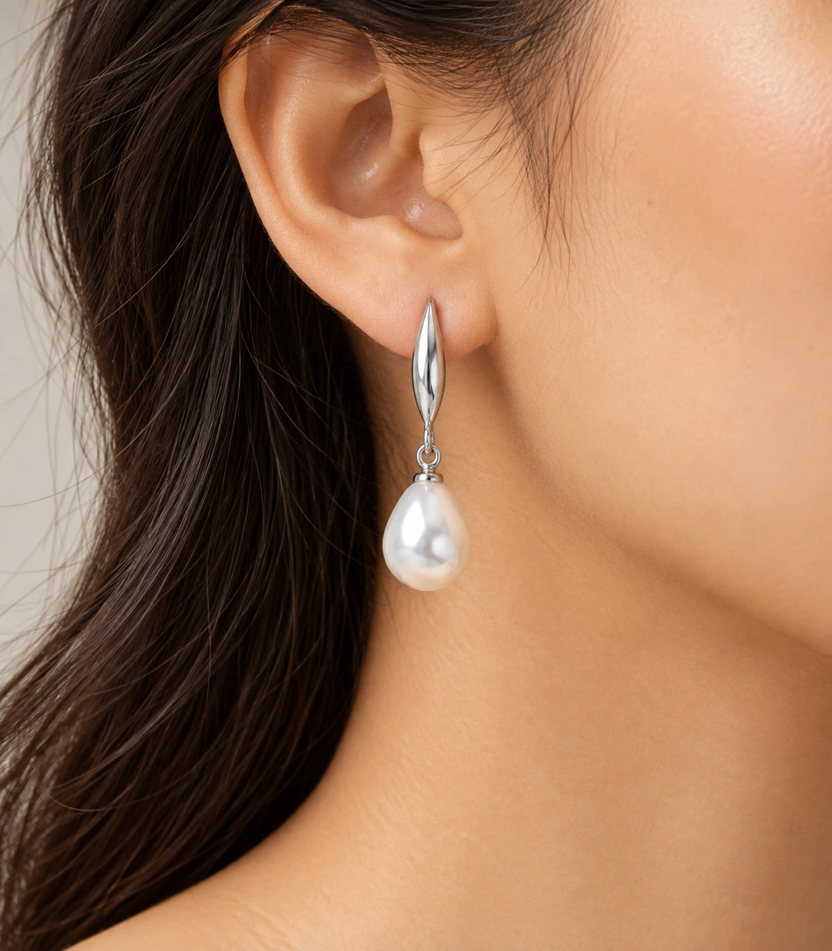 Styled wearing view showing a silver-tone leaf earring and white teardrop pearl-style drop
