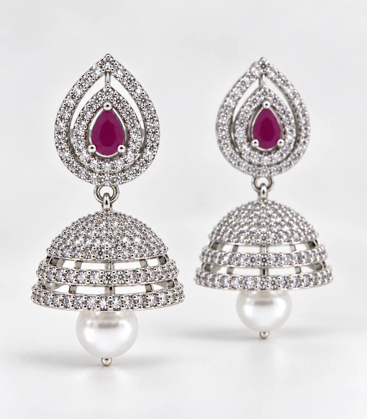 Matching pair of silver-tone magenta double halo jhumka earrings arranged on a light surface