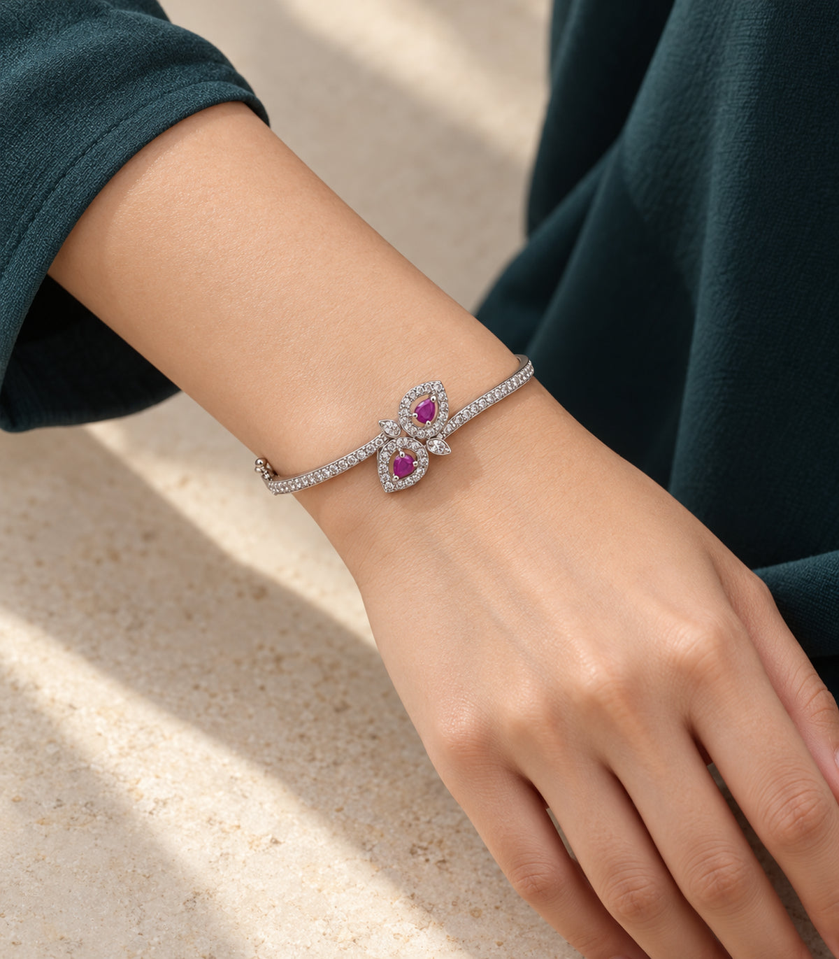 Silver magenta double leaf bangle worn on a wrist beside a teal sleeve