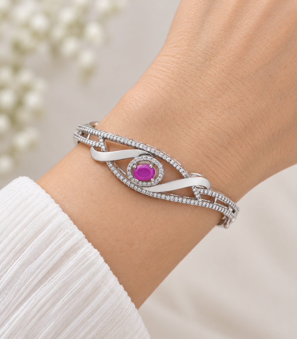 Close view of the magenta oval halo and crossed ribbon bangle worn on a wrist
