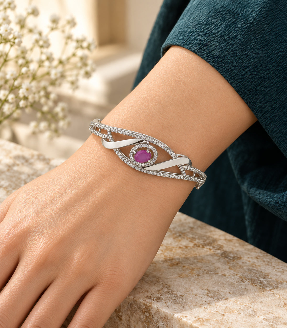 Silver magenta oval ribbon bangle worn with a dark teal sleeve