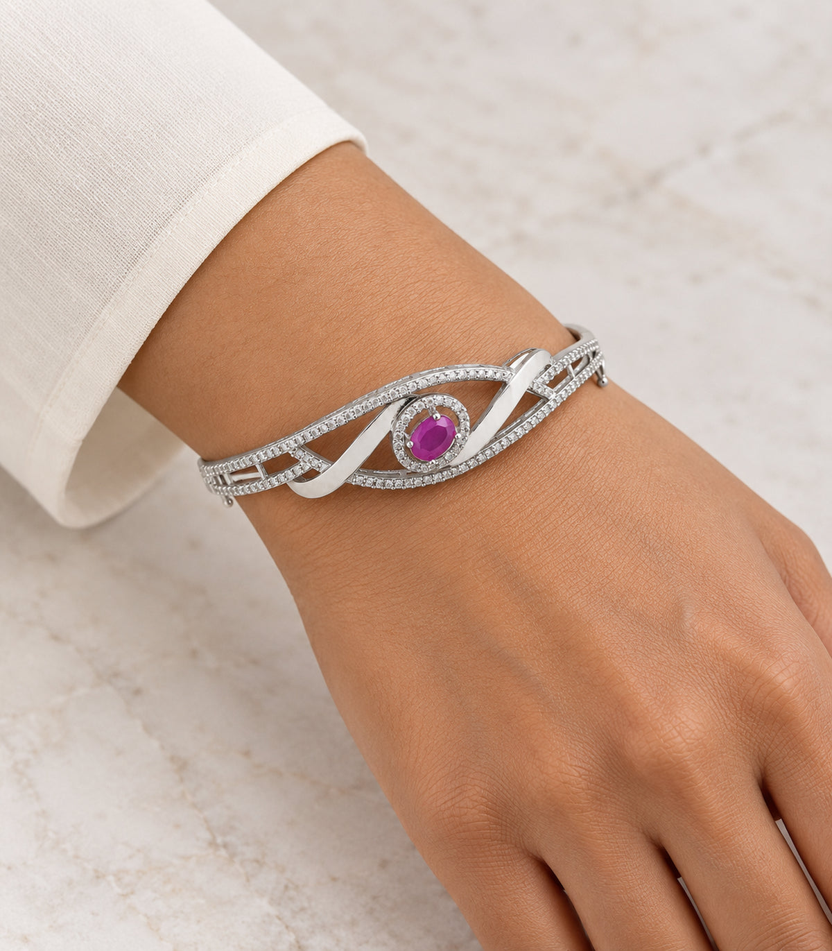 Silver magenta oval ribbon bangle worn on a wrist with an ivory sleeve