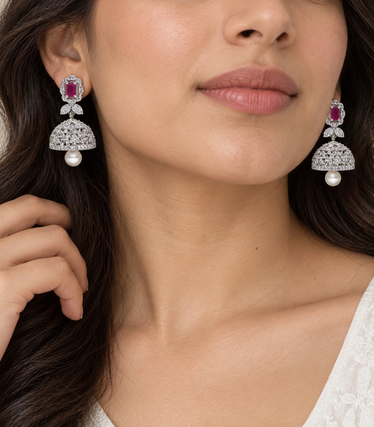 Magenta rectangular bow pearl-style jhumka earrings shown worn in close view
