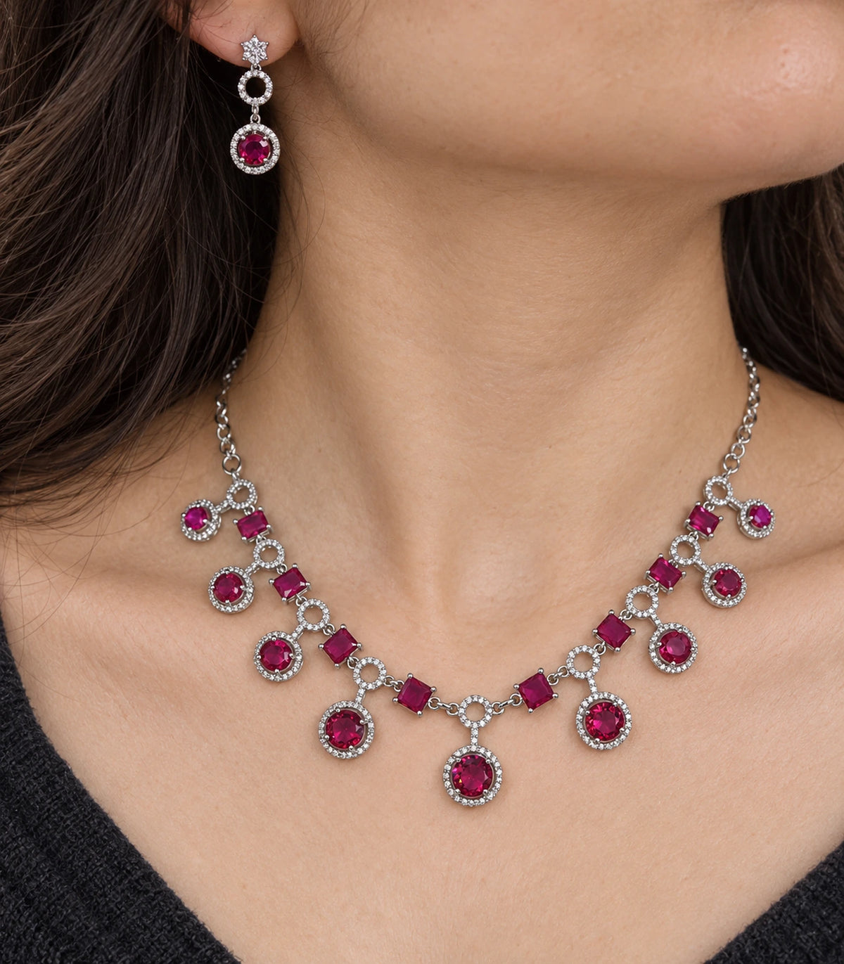 Close view of the silver-tone magenta necklace and one matching earring worn naturally