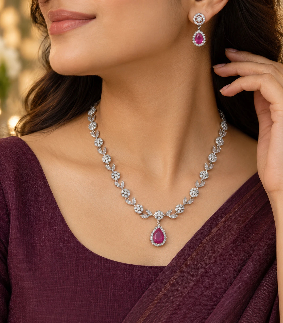 Angled worn view of the silver-tone necklace and magenta teardrop earring