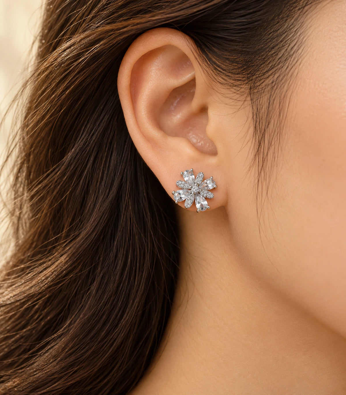 Silver-tone floral stud earring worn on an ear in warm light