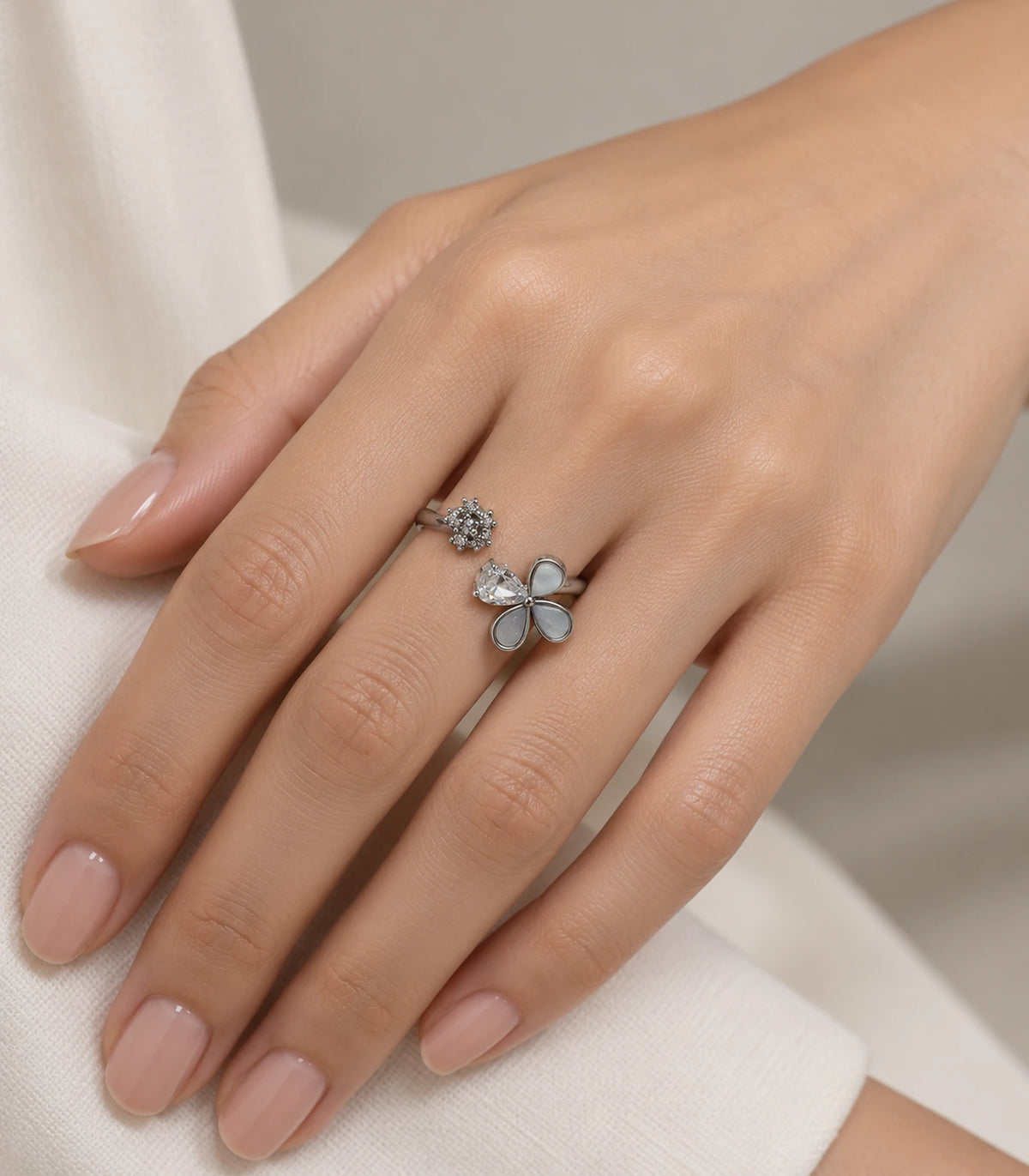 Silver-tone flower and crystal open ring worn on a finger