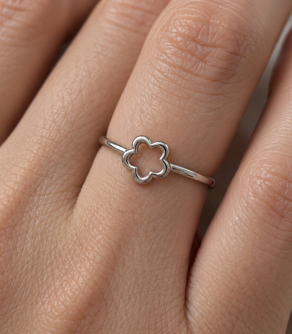 Close view of the plain five-petal flower outline ring worn on a finger