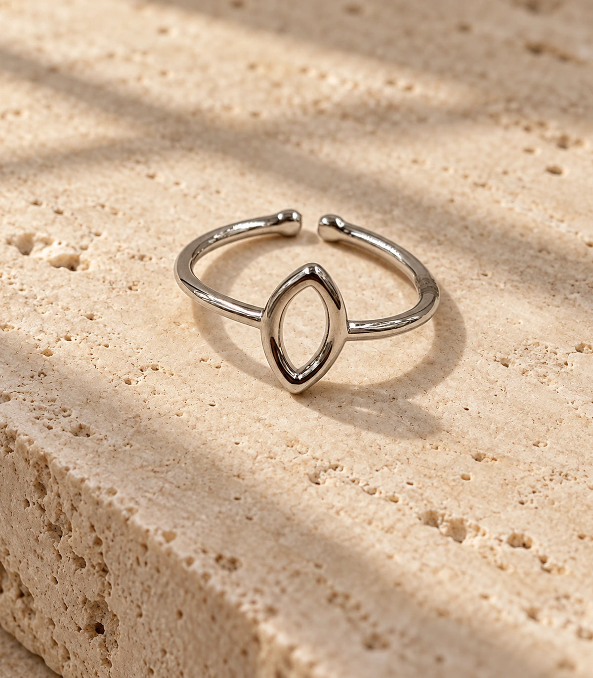 Complete silver-tone open-back marquise ring on a stone styling surface