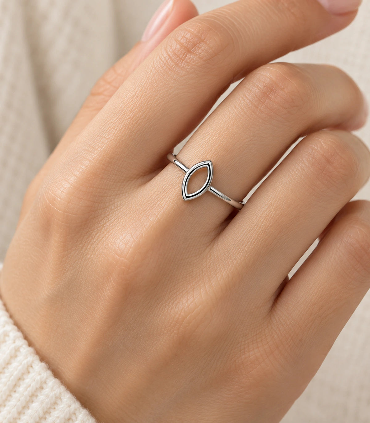 Silver-tone hollow marquise ring worn on a finger with a cream knit cuff
