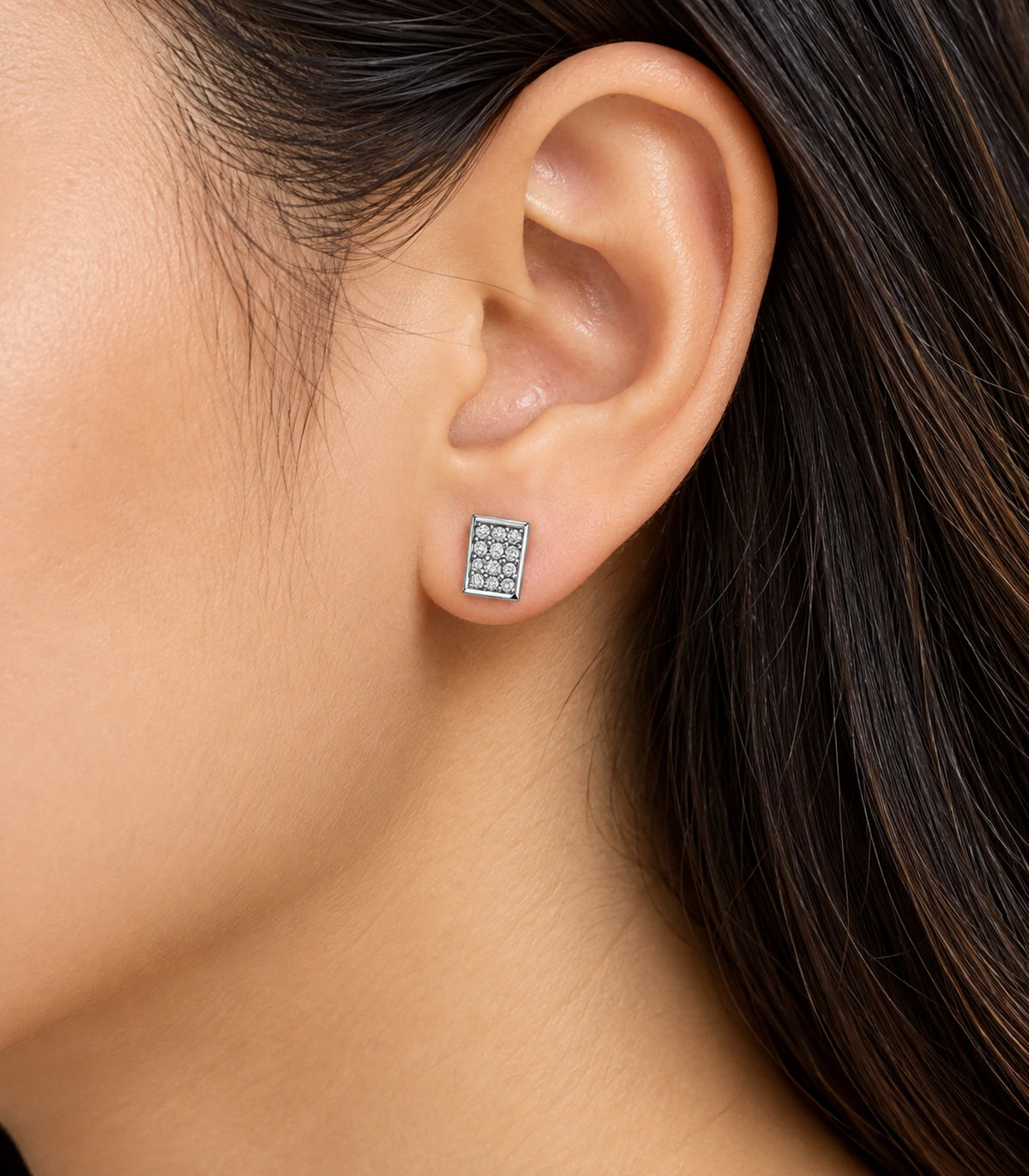 Silver-tone rectangular pavé stud earring worn on the ear in a side detail view