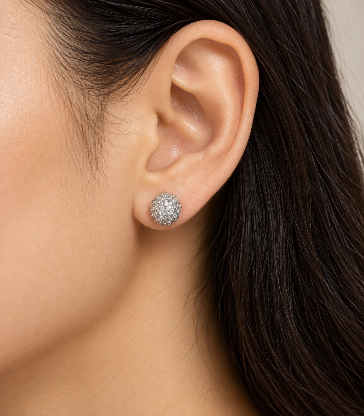 Silver-tone pavé sphere stud earring worn at the ear
