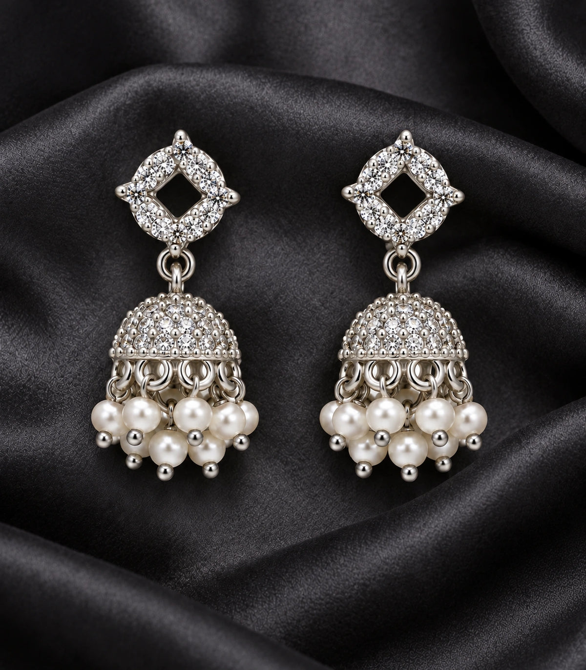 JIMIKI Silver Quatrefoil Crystal Jhumka Earrings - Matching pair on textured black fabric #color_silver
