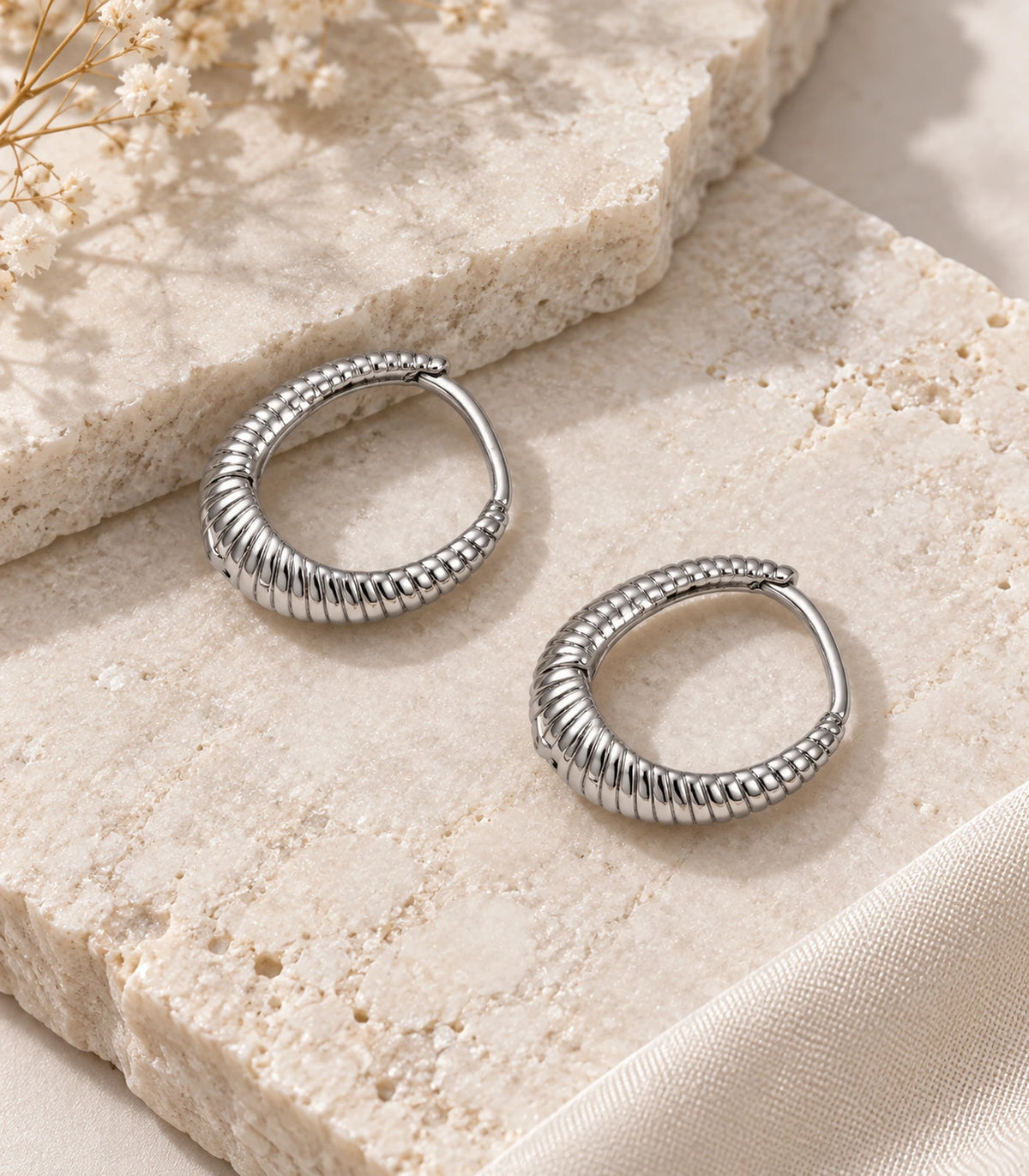 JIMIKI Ribbed Teardrop Hoop Earrings in Silver - editorial flatlay #color_silver