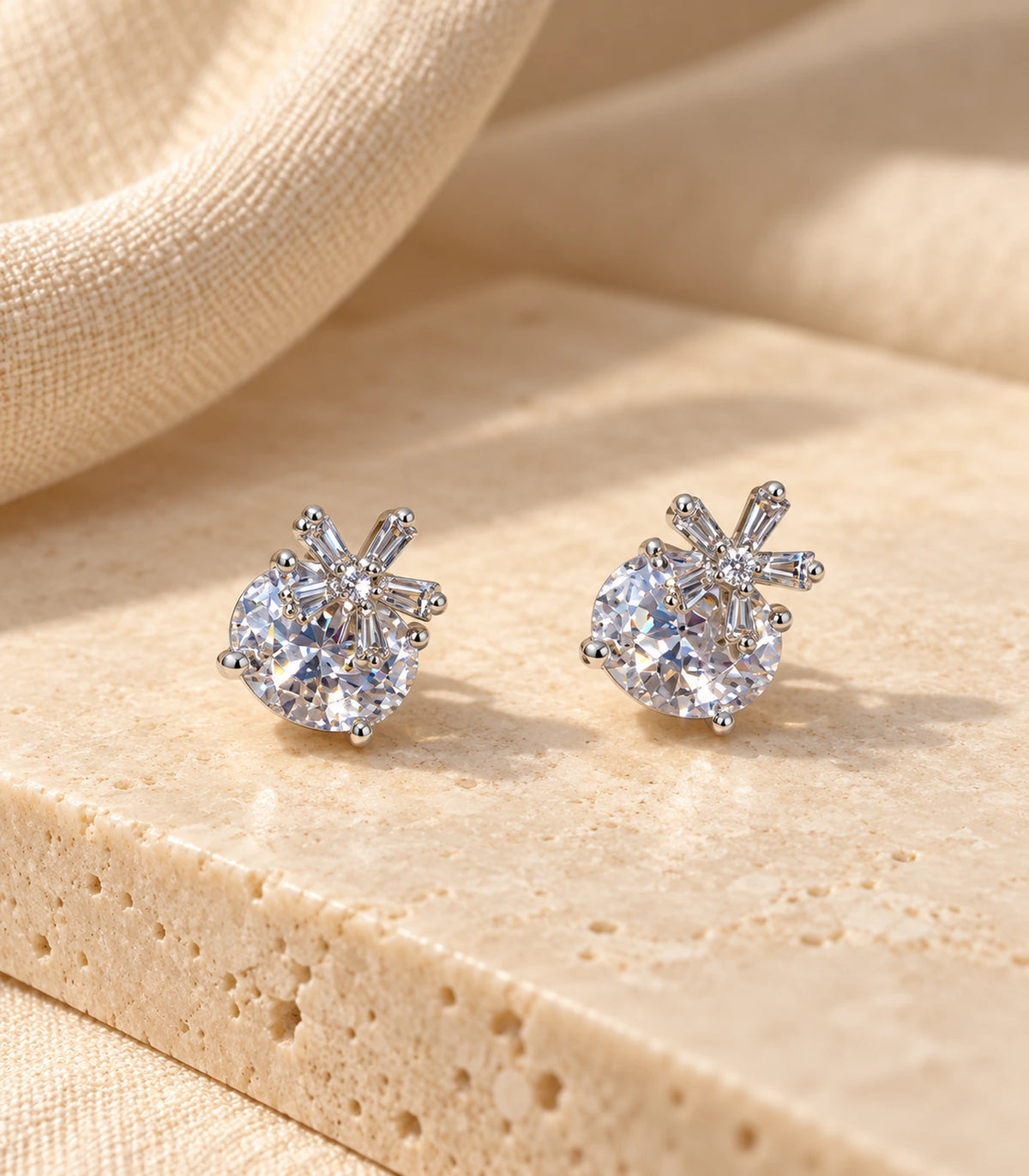 Pair of silver-tone round crystal-style stud earrings with baguette burst accents styled on stone