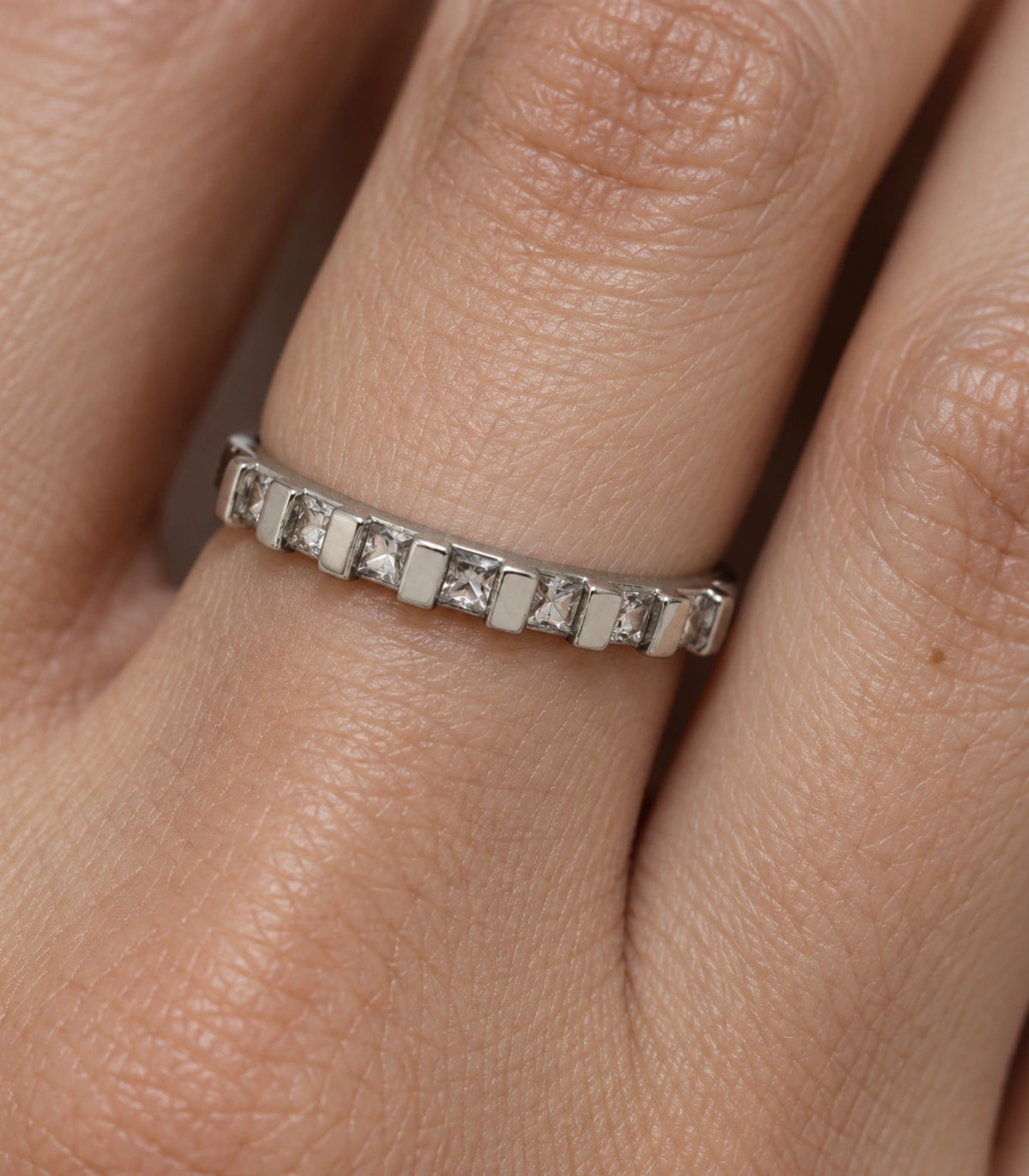 Close view of the seven square clear crystals and silver bars on the worn ring