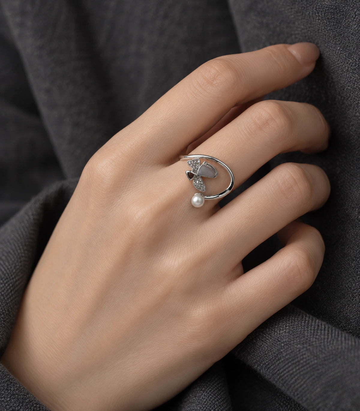 Silver swirl pearl crystal open ring worn on a hand against dark fabric