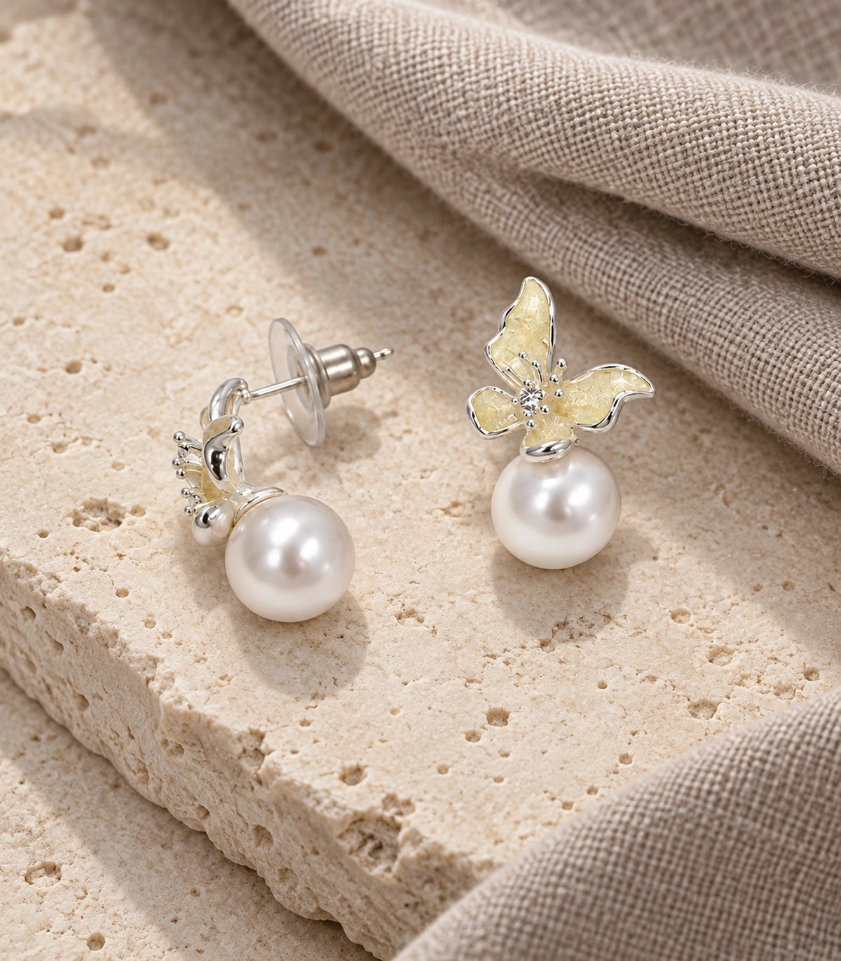 JIMIKI Asymmetric Butterfly Pearl-Style Earrings in Cream / silver-tone / white, editorial flat lay #color_cream / silver-tone / white